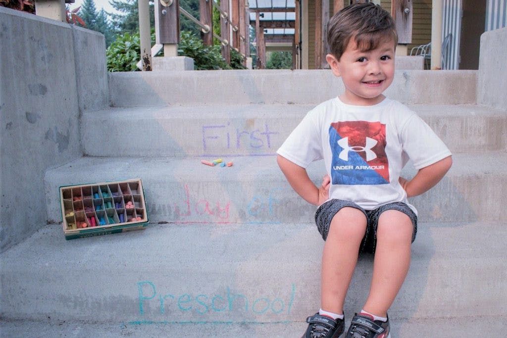 Child sitting on concrete steps with a box of chalk