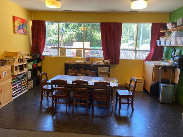 Classroom with a long table and chairs, shelves, and large windows
