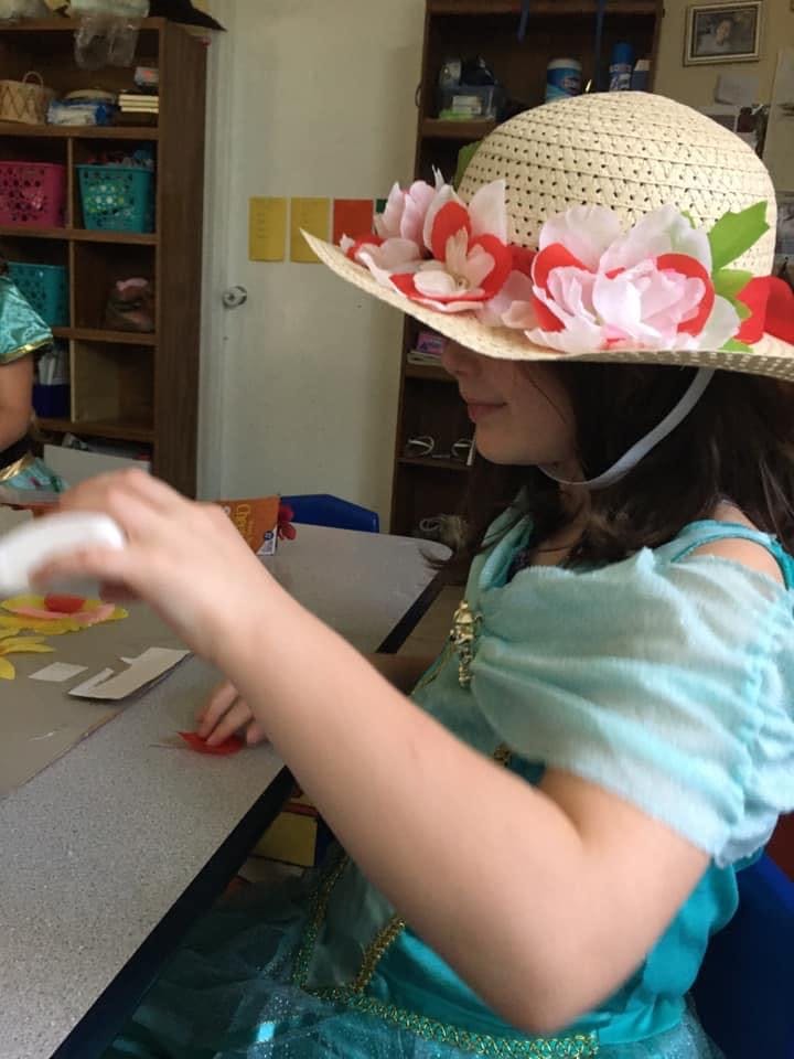 Child in a floral hat working on a craft project