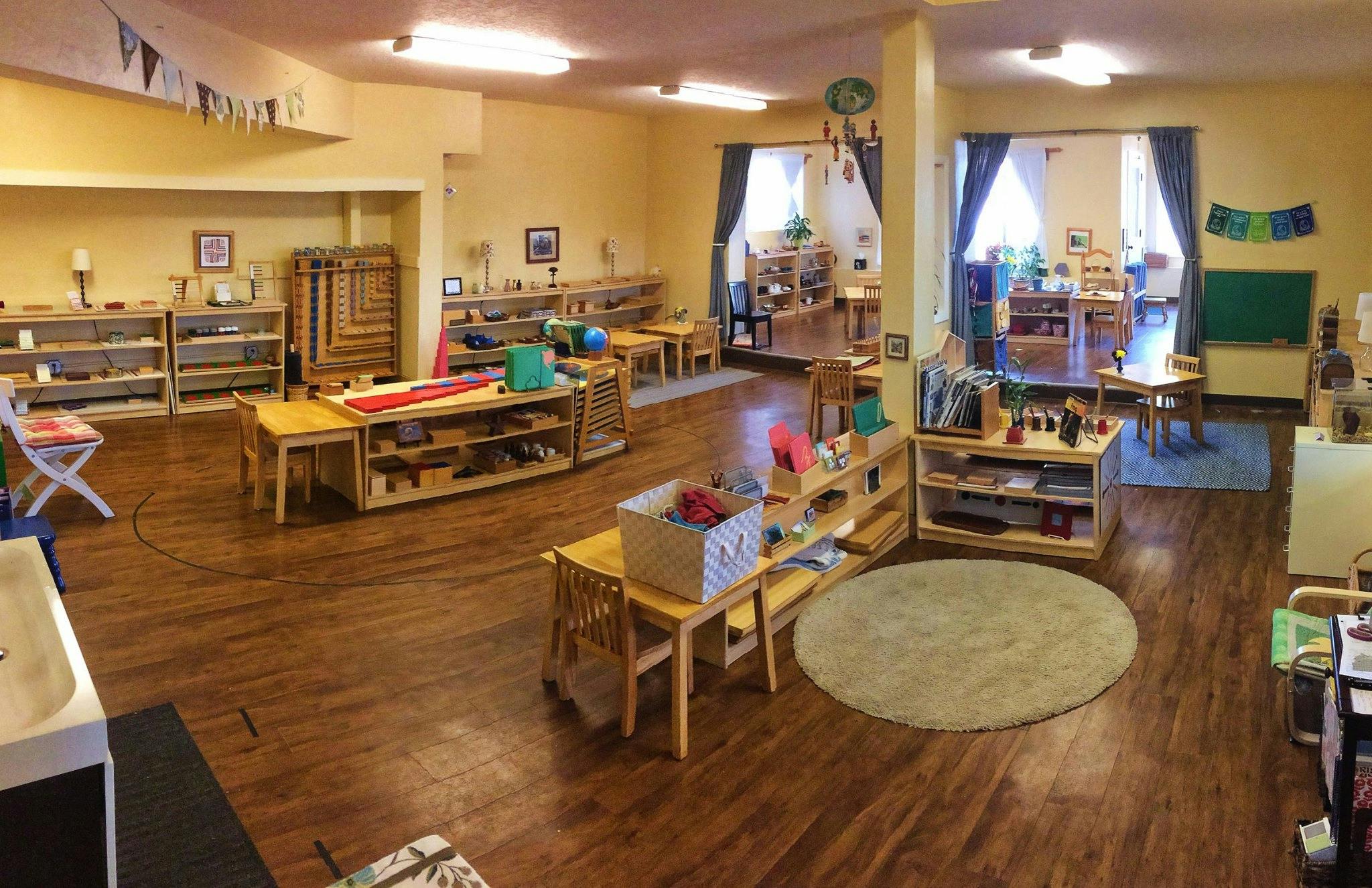 Classroom with wooden furniture, shelves, and a round rug