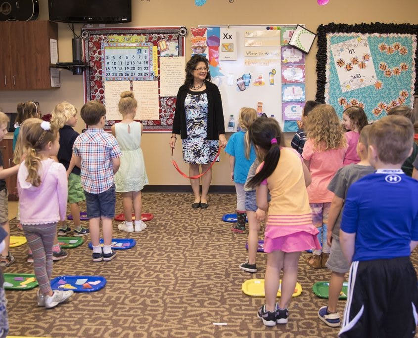 Adult person leading a group of children in a classroom
