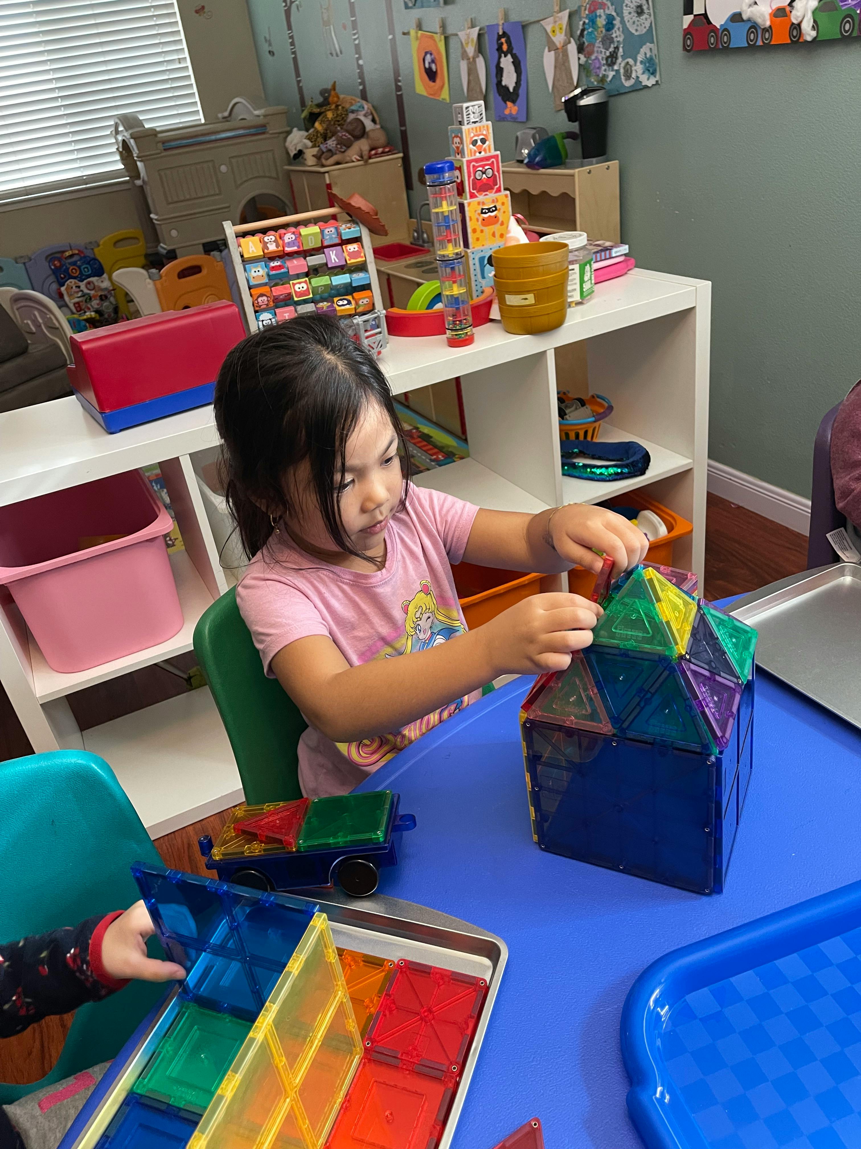 Child building a structure with colorful magnetic tiles at a table