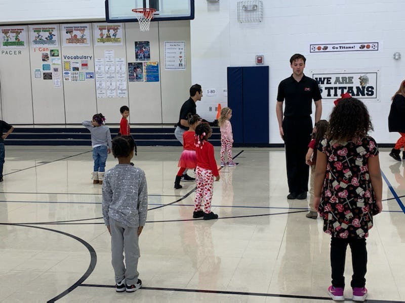 Adults and children standing on a gymnasium floor