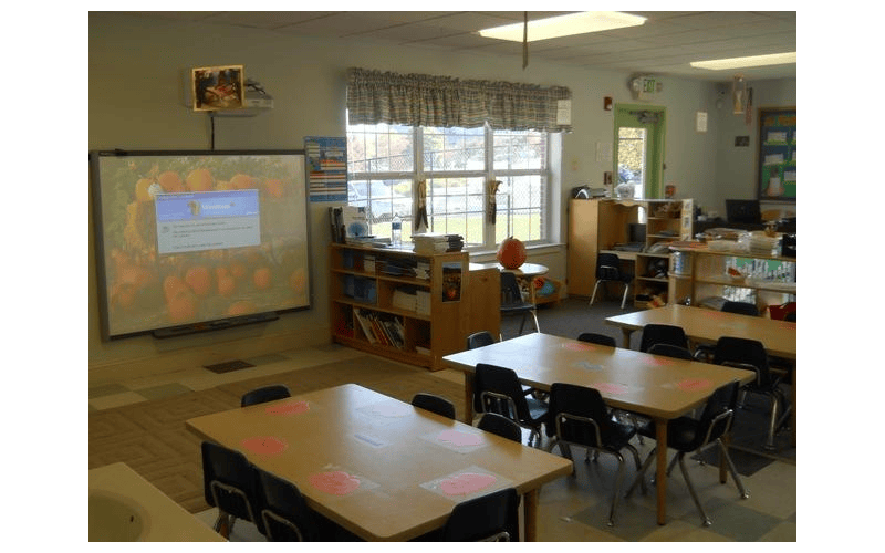 Classroom with tables, chairs, bookshelves, and an interactive whiteboard