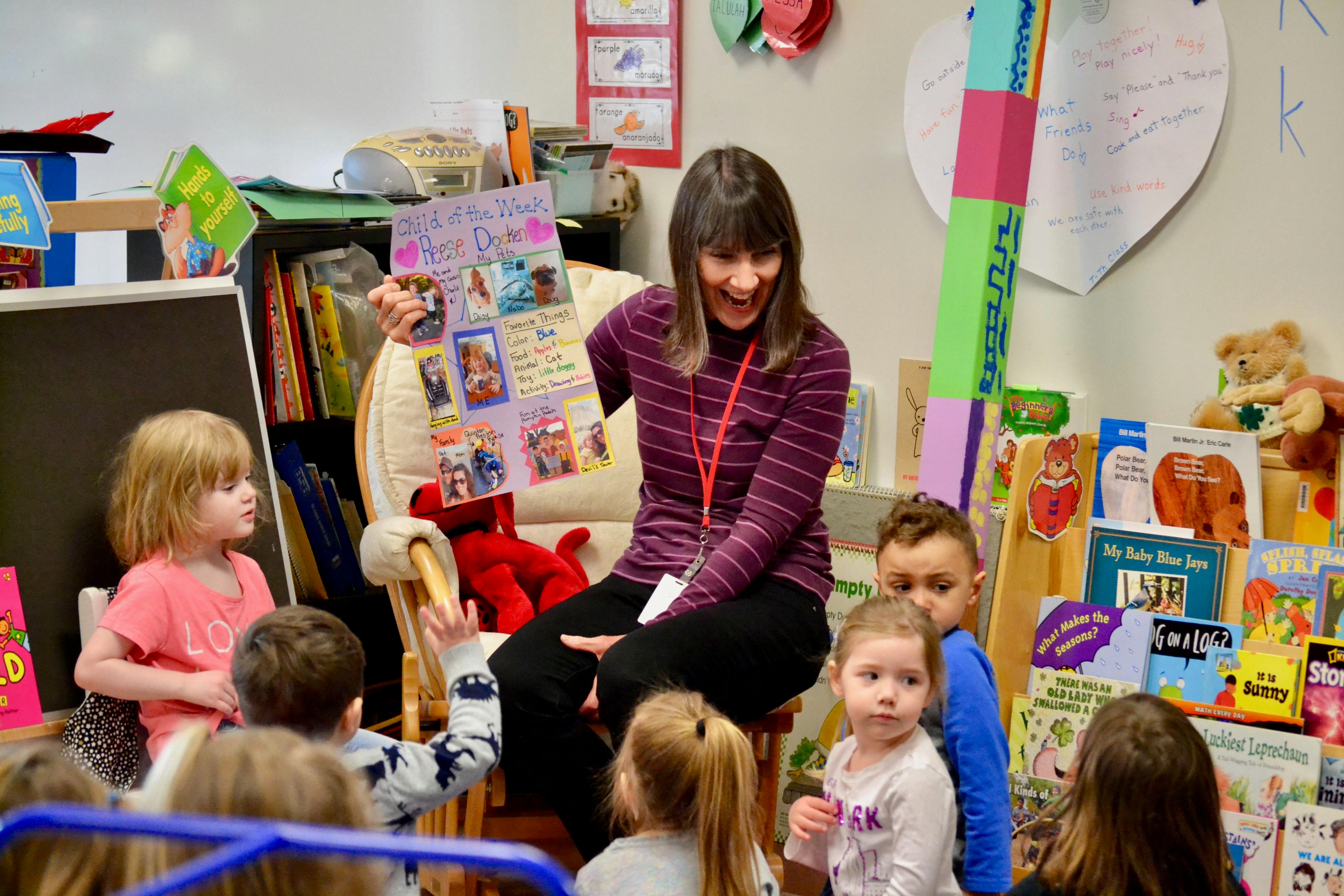 Person showing a poster to children in a classroom