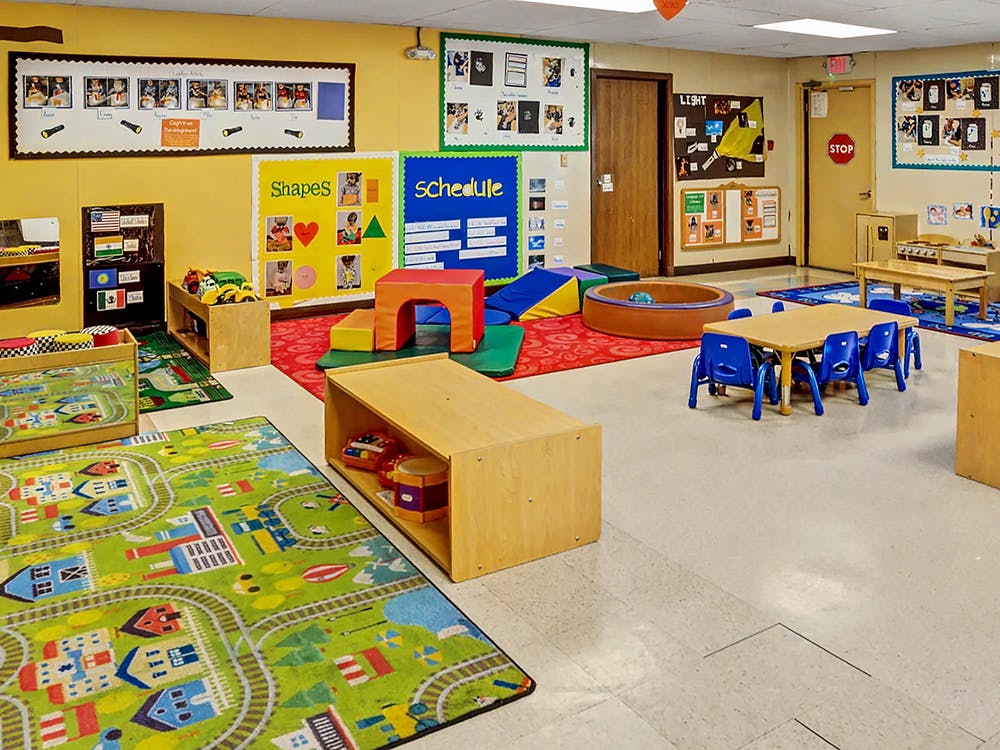 A colorful empty classroom with toys, small tables, and learning posters