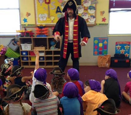 Person in pirate costume standing in front of children sitting on floor