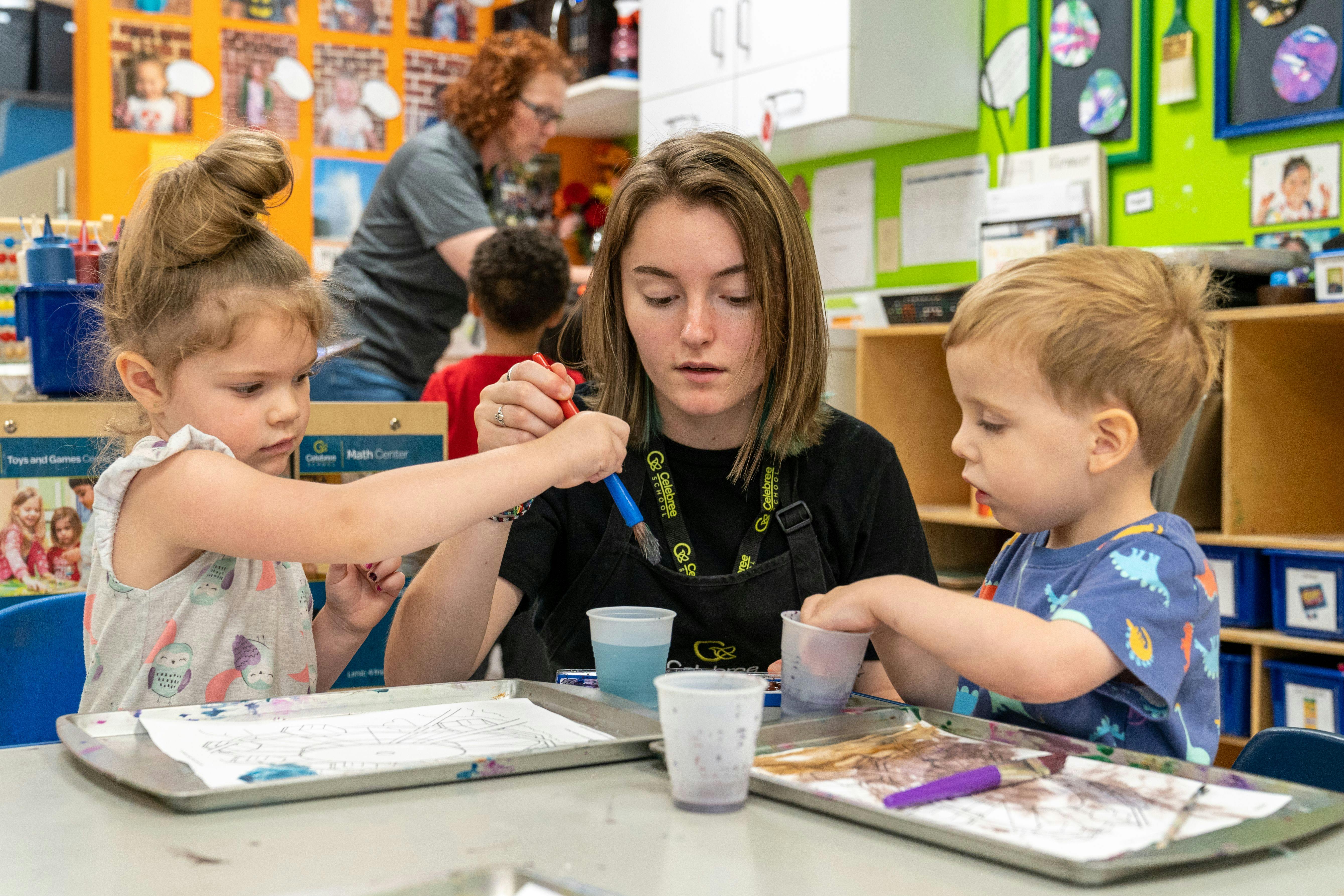 Adult and two children doing an art activity at a table