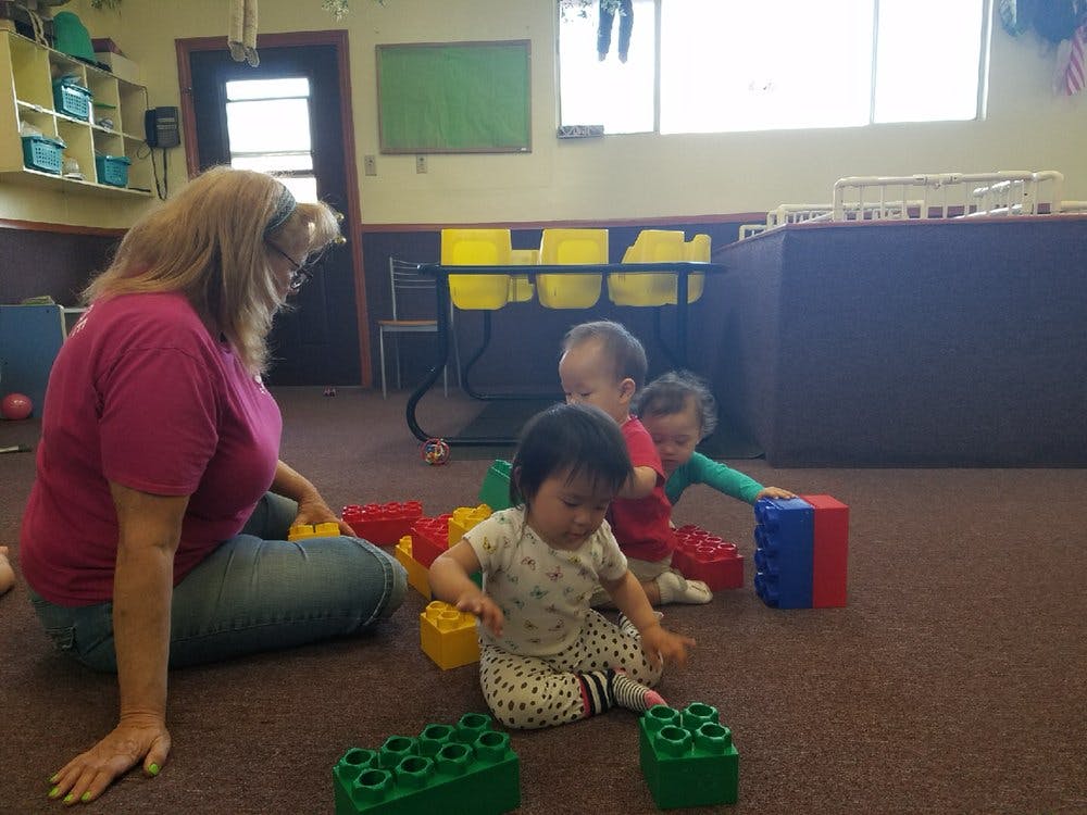 Person and children playing with large building blocks on the floor