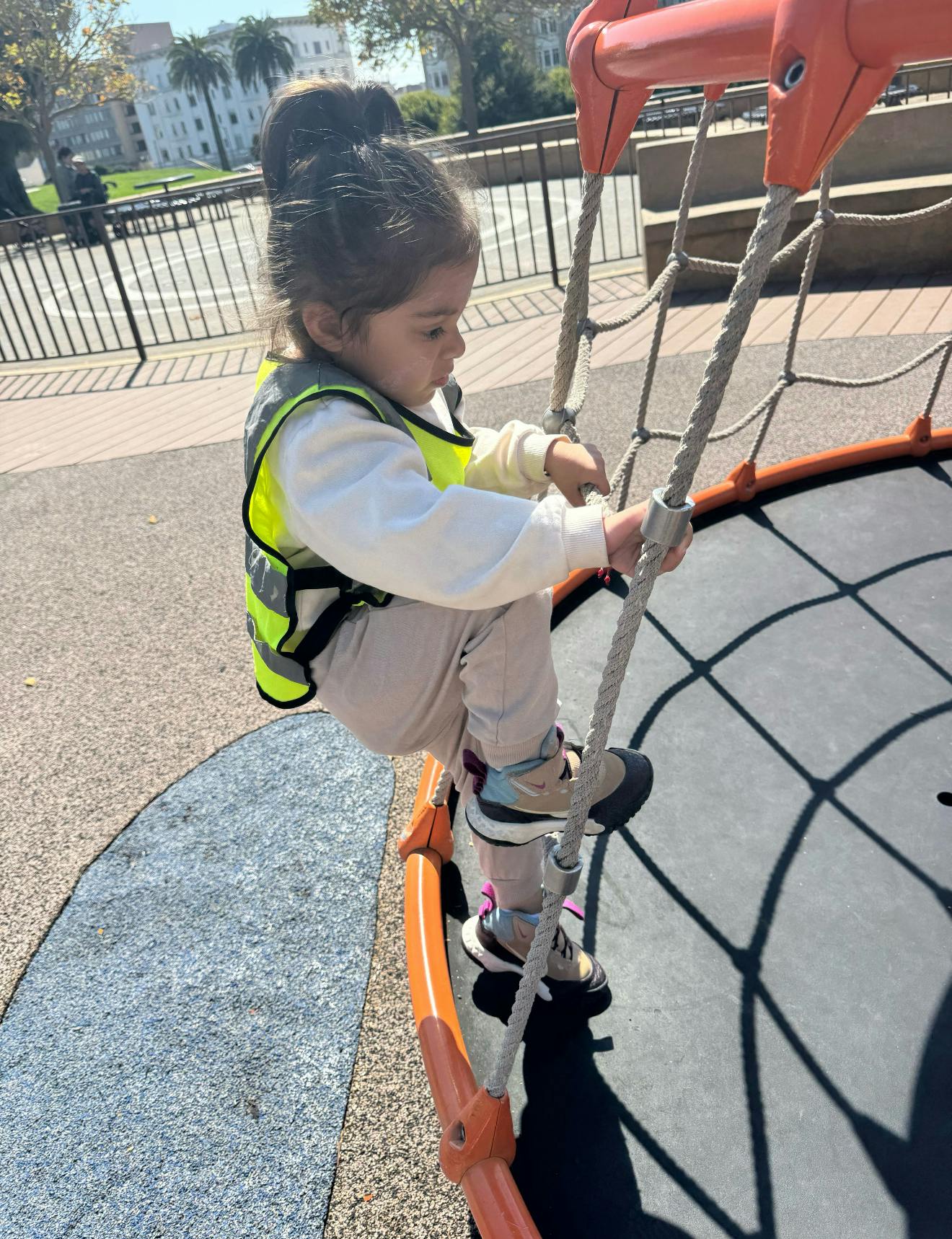 Child climbing a rope net structure on a playground