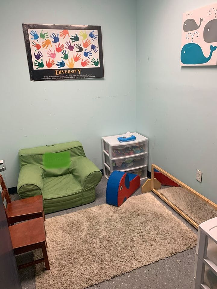 Room with a green chair, rug, and a poster with colorful handprints and "DIVERSITY"