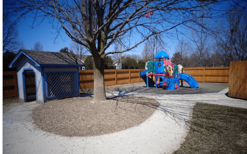 Playground with a small playhouse, tree, and colorful play structure