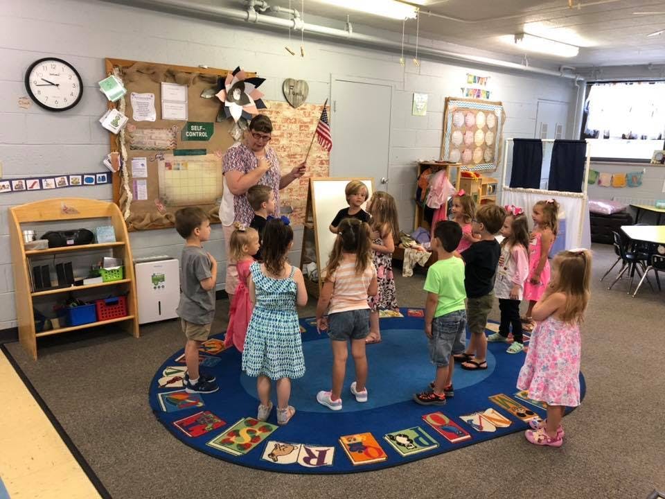 Adult leading a group of children in a classroom