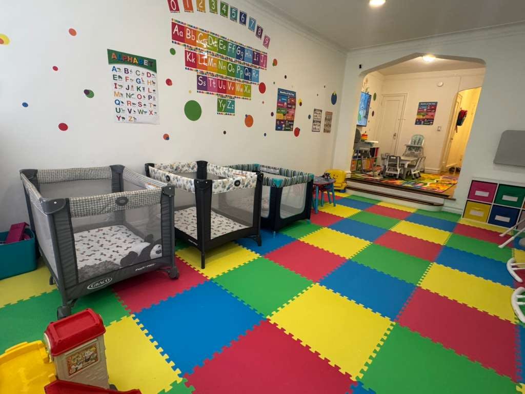 cribs in a play area with colorful floor mats and alphabet decorations