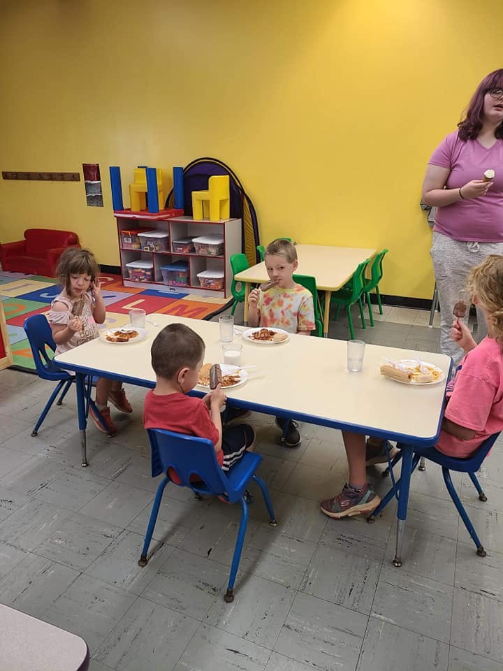 Children and an adult sitting at tables in a classroom