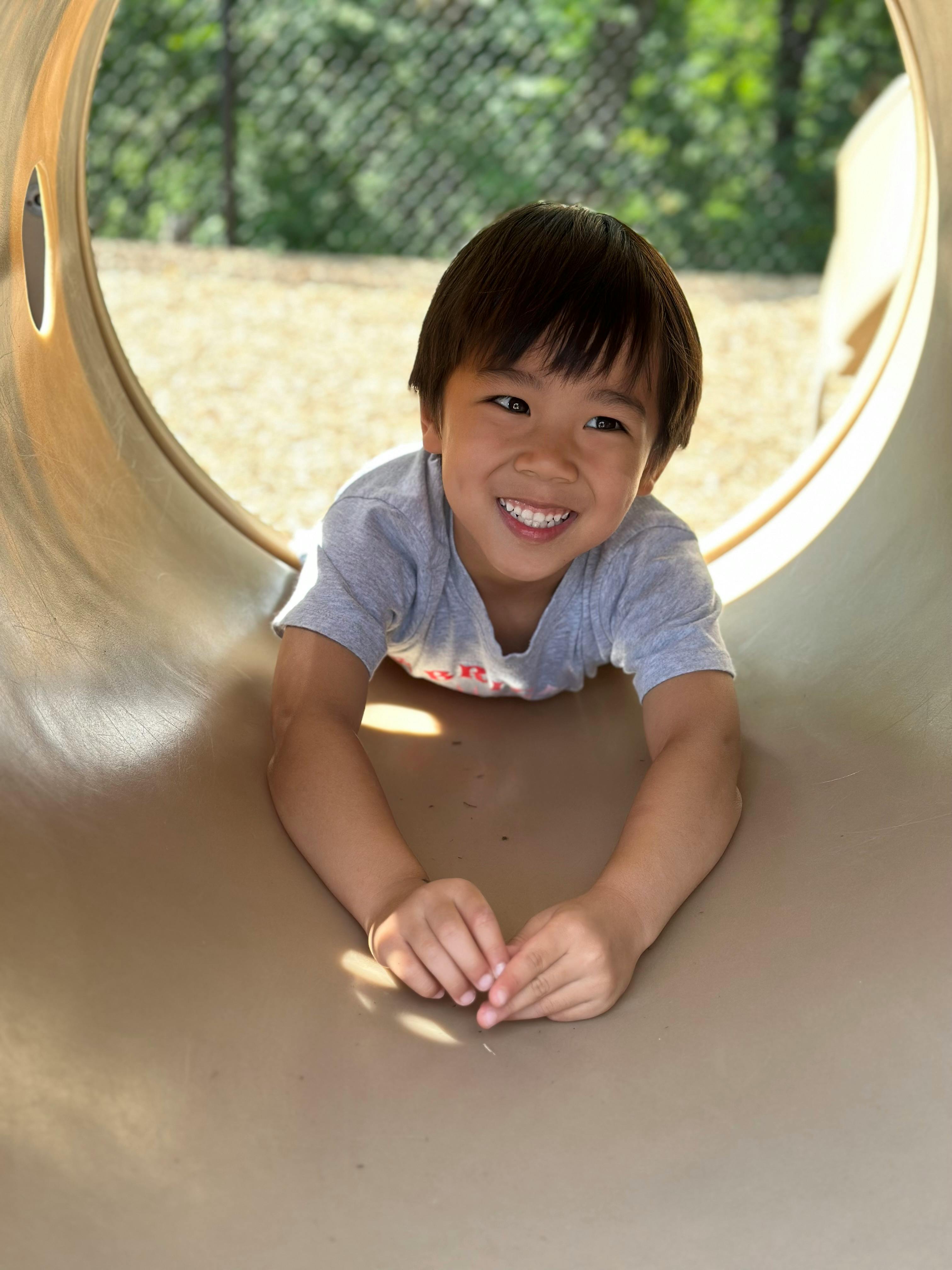 Child smiling while lying in a tunnel on a playground tunnel