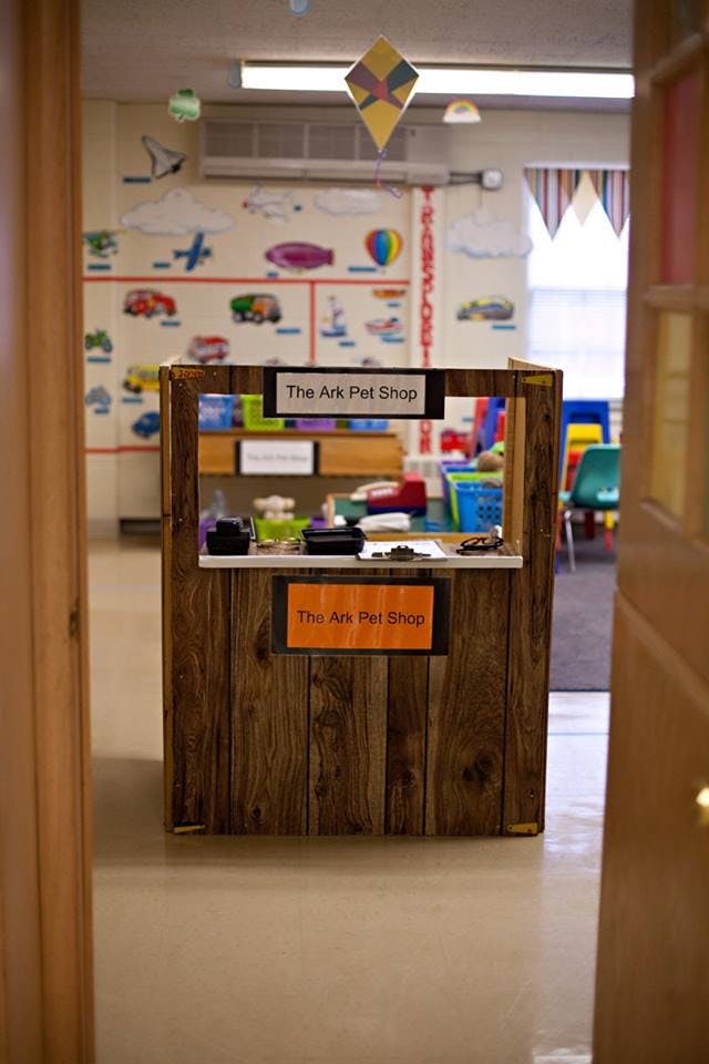 A wooden play stand with "The Ark Pet Shop" signs in a classroom