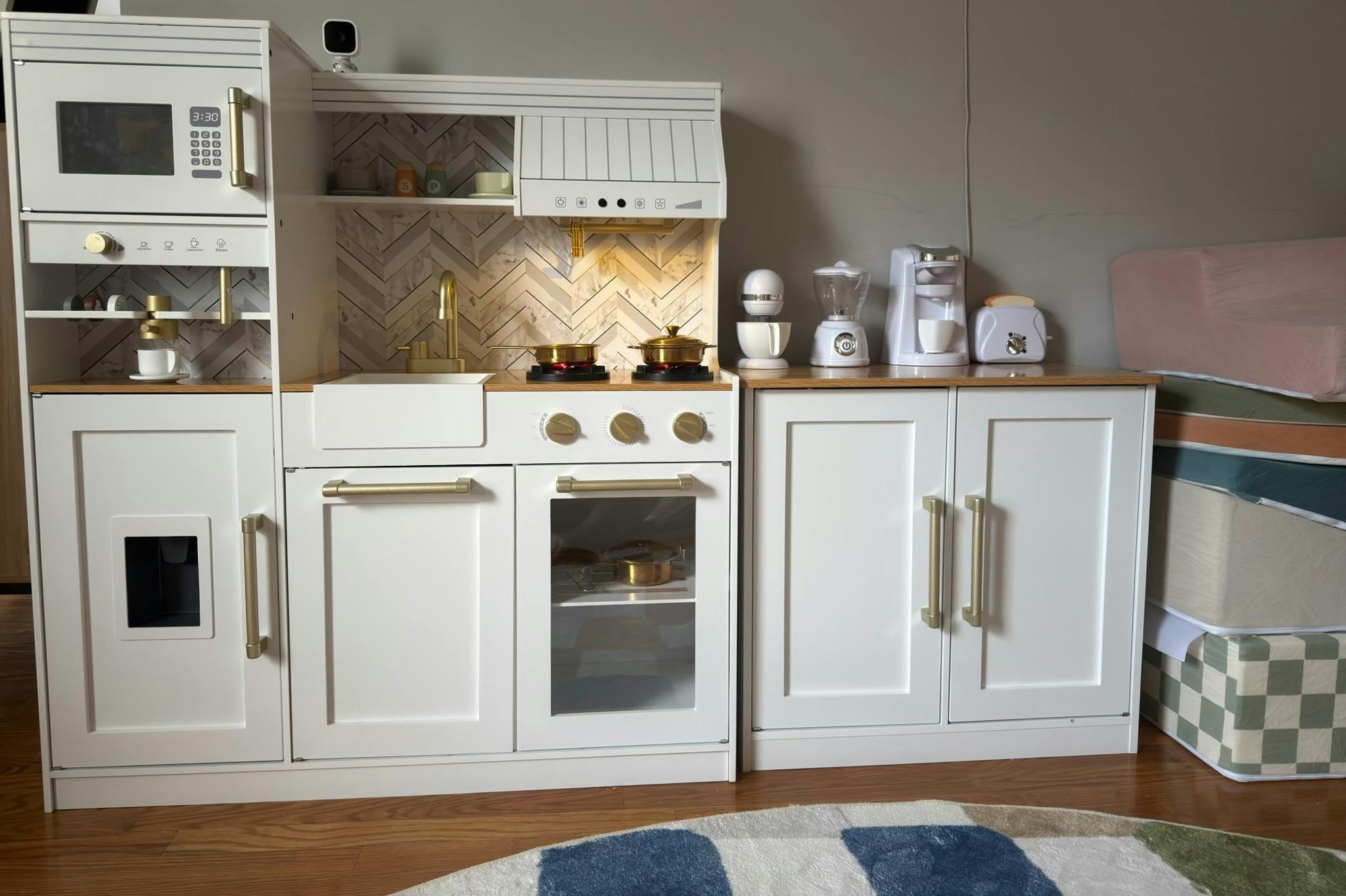 White toy kitchen set with gold hardware and small toy appliances