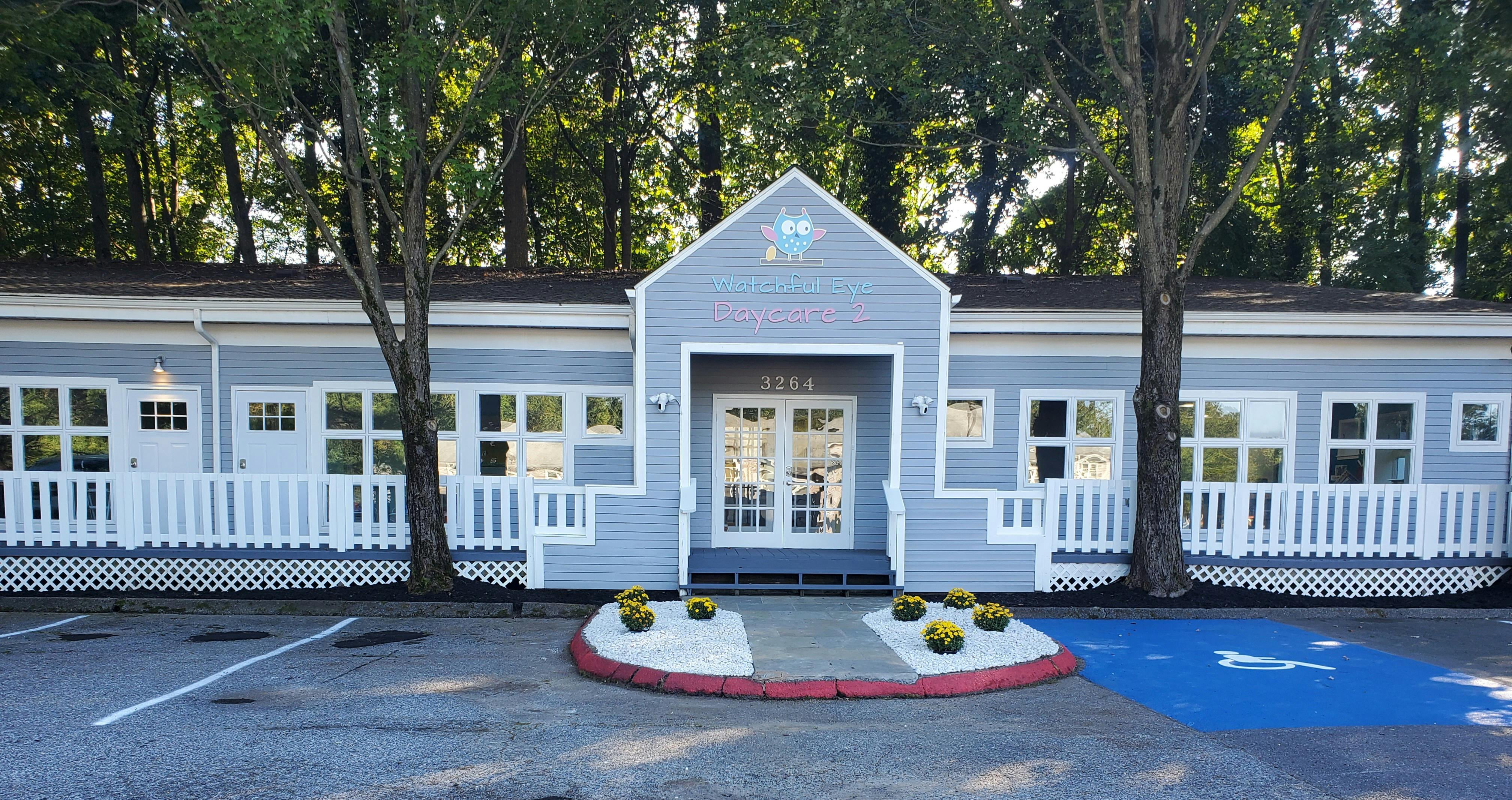 Exterior of a light blue building with white trim and a small garden