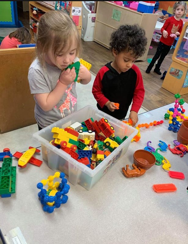 Two children playing with building blocks and toys at a table