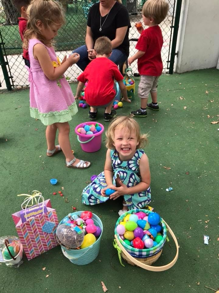 Children and an adult playing with colorful plastic eggs and baskets outdoors