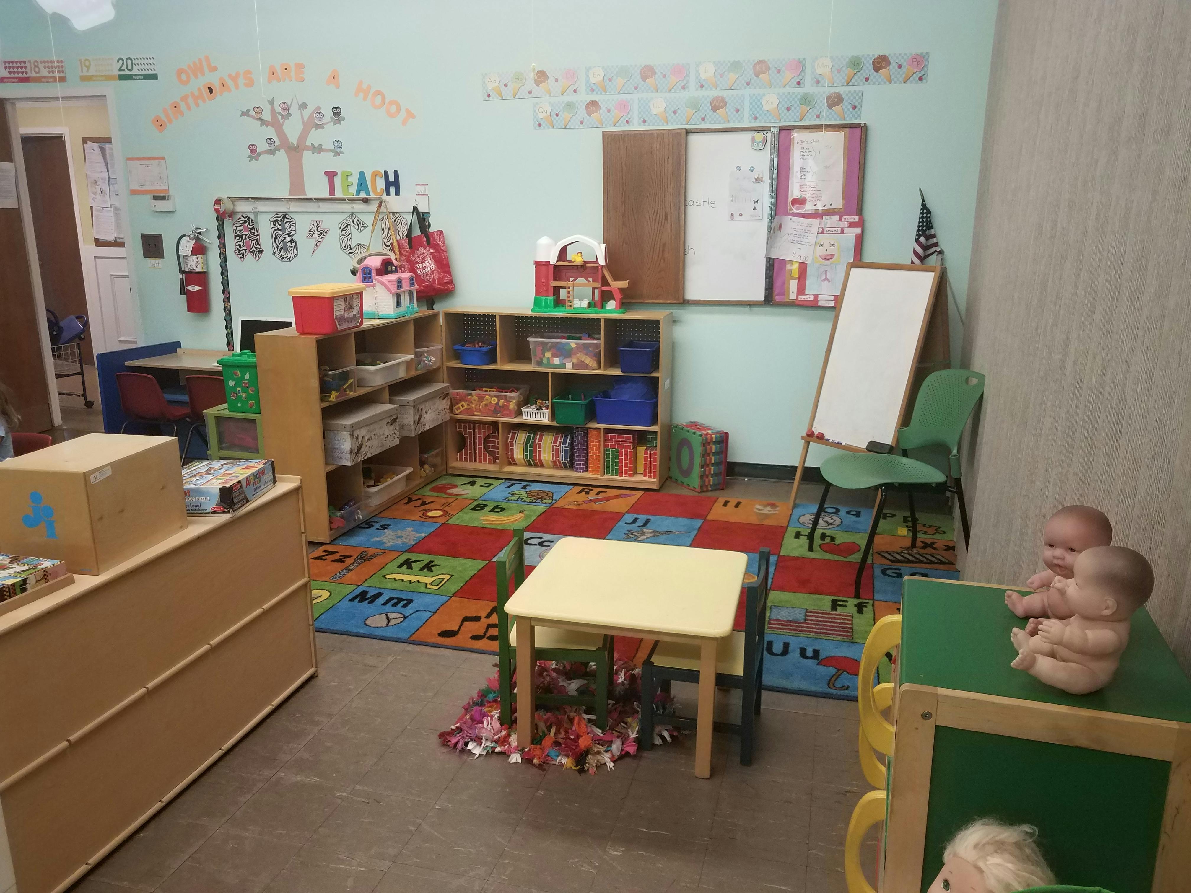 A colorful classroom with small tables, shelves, and a whiteboard