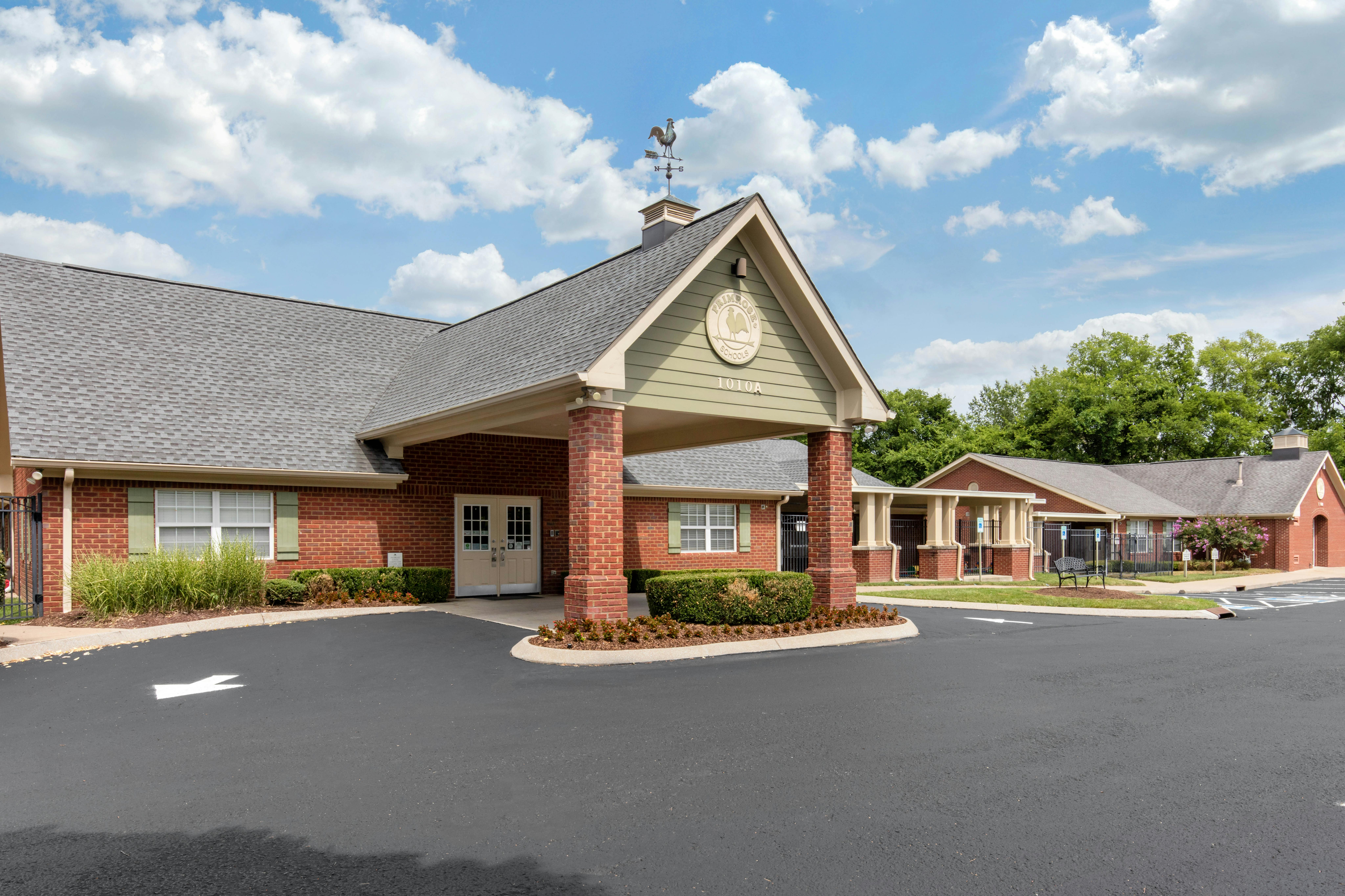 Brick building with a prominent covered entrance and a sign reading "Primrose Schools"