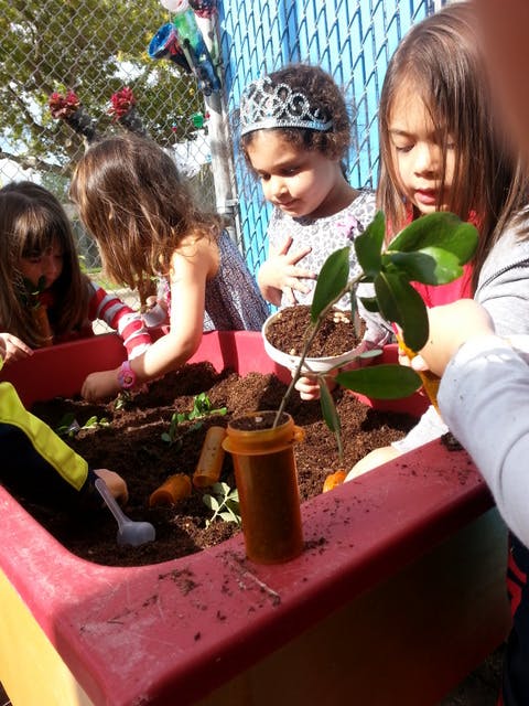 Children planting in a red planter
