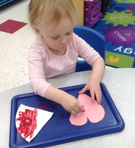 Child doing an art activity with paper hearts and paint