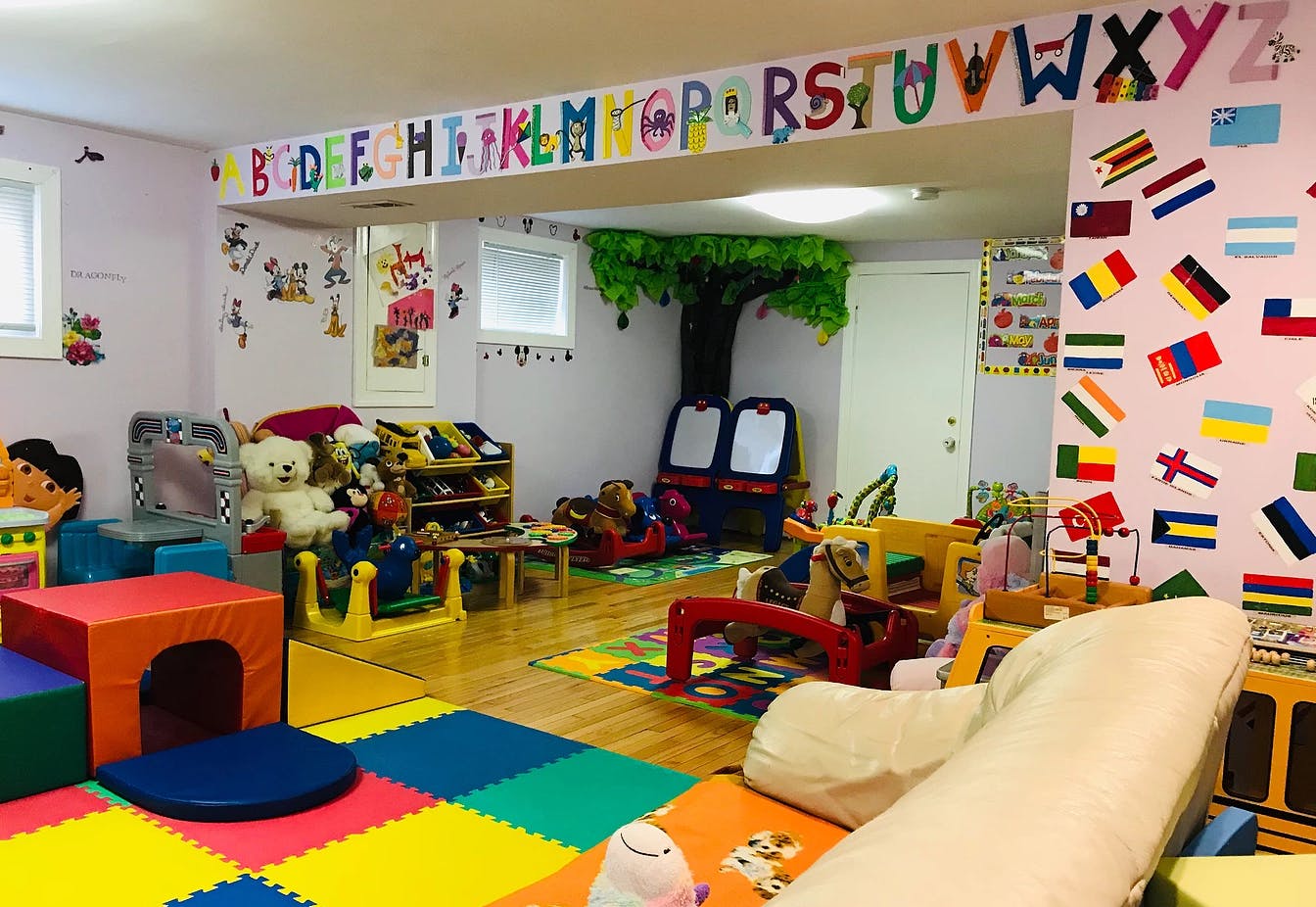 Playroom with colorful alphabet banner, floor mats, and toys