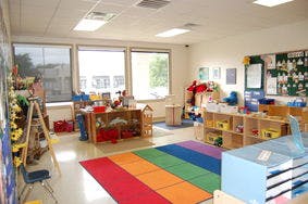 Classroom with a rainbow rug and various learning stations