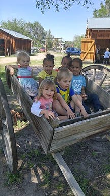 Six children sitting in a wooden wagon