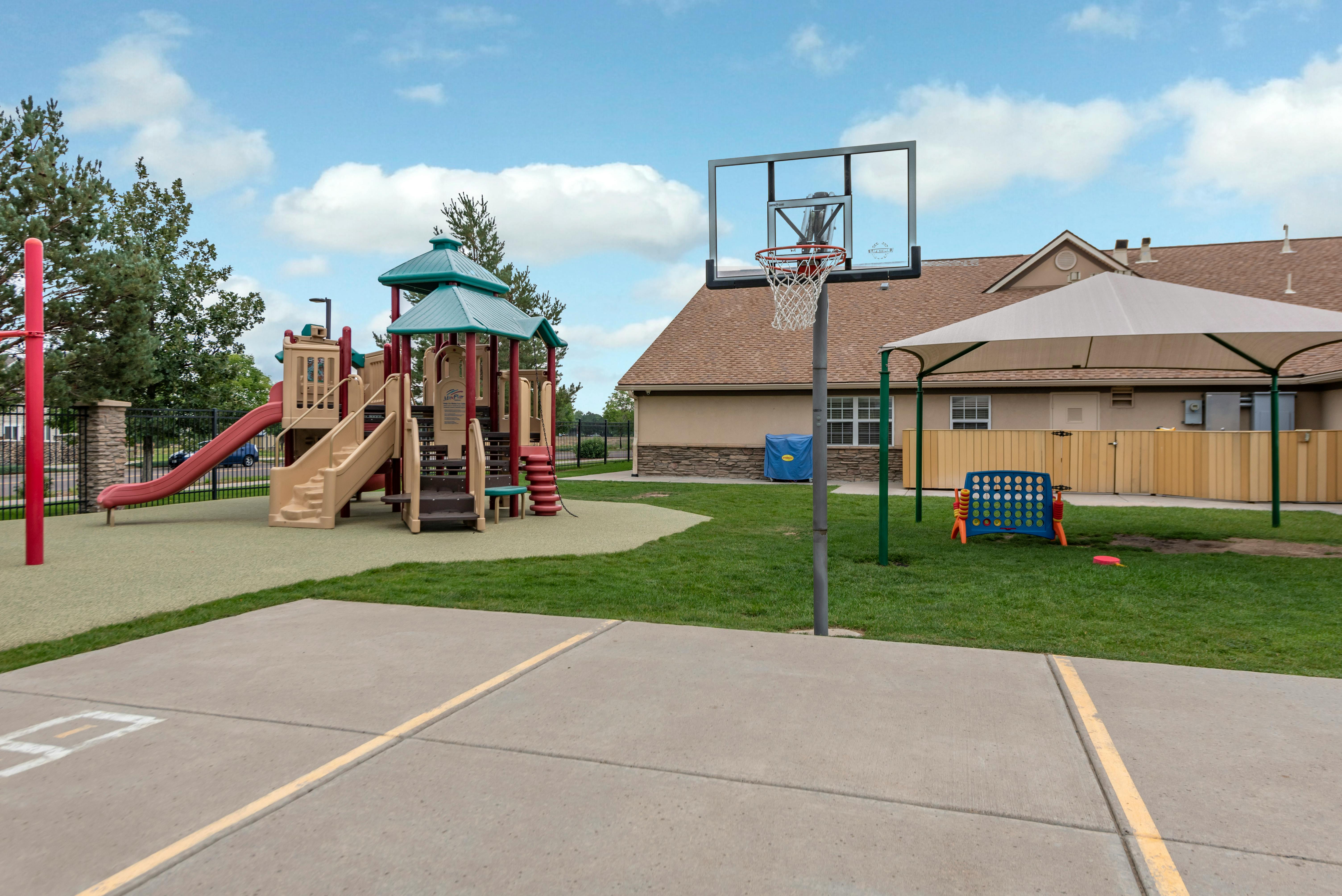 Outdoor playground with a slide, swings, basketball hoop, and Connect Four game