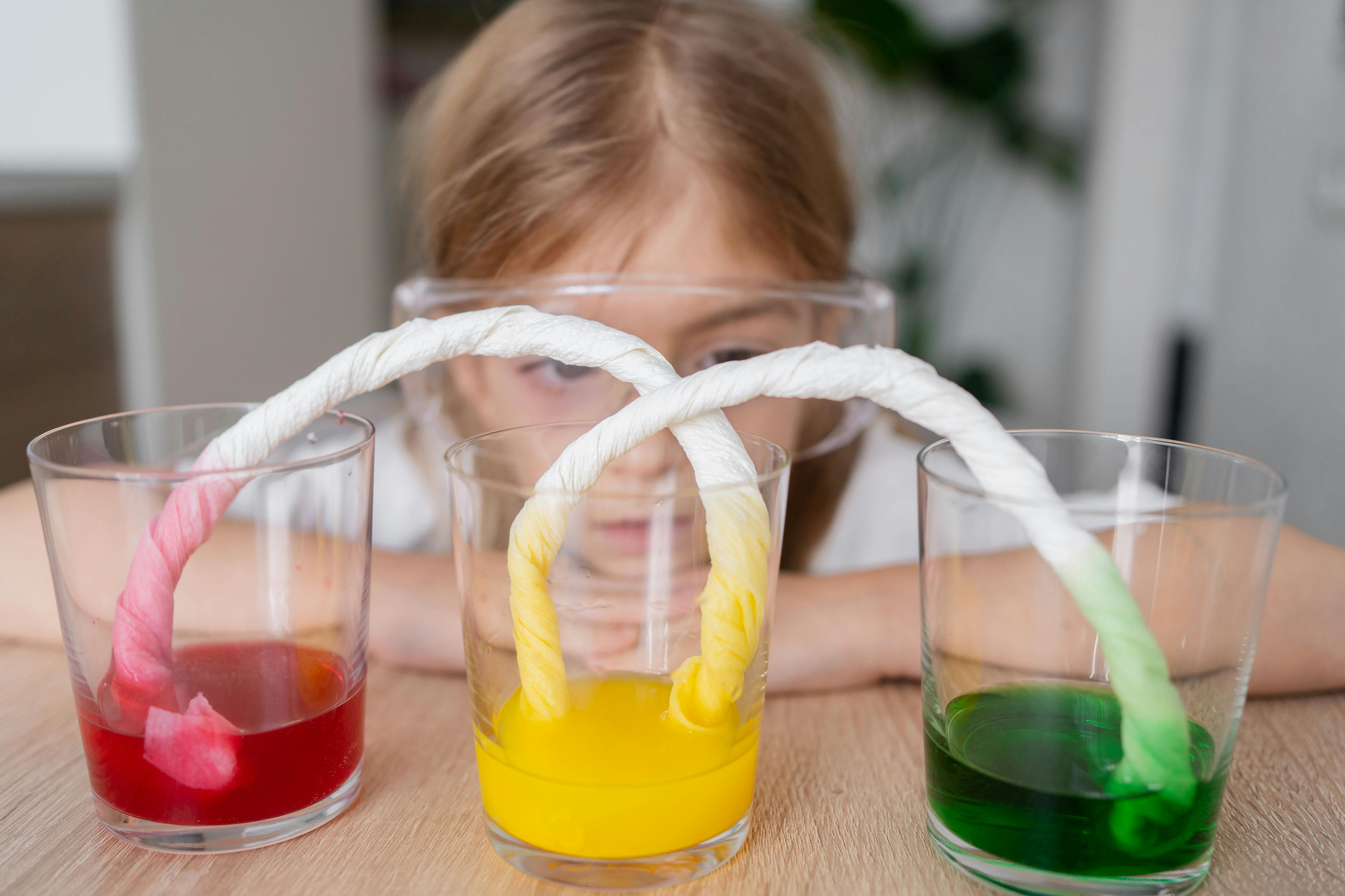 Child in safety goggles doing a science experiment with colored liquids