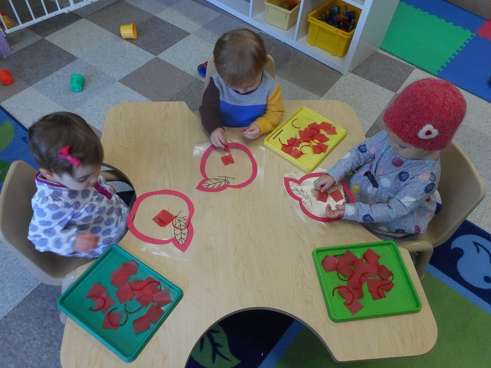 Three children at a table playing with red shapes