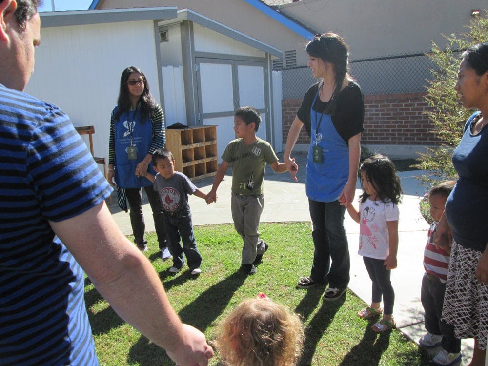 People and children holding hands in a circle outdoors