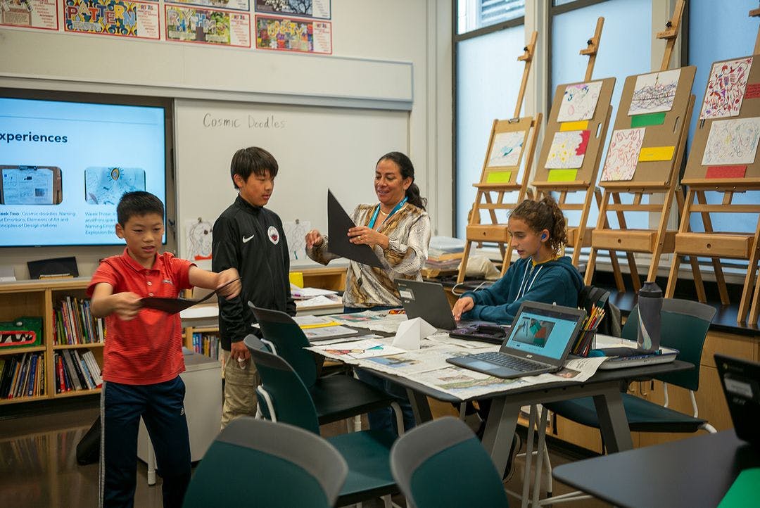 A teacher interacting with three children at a classroom table