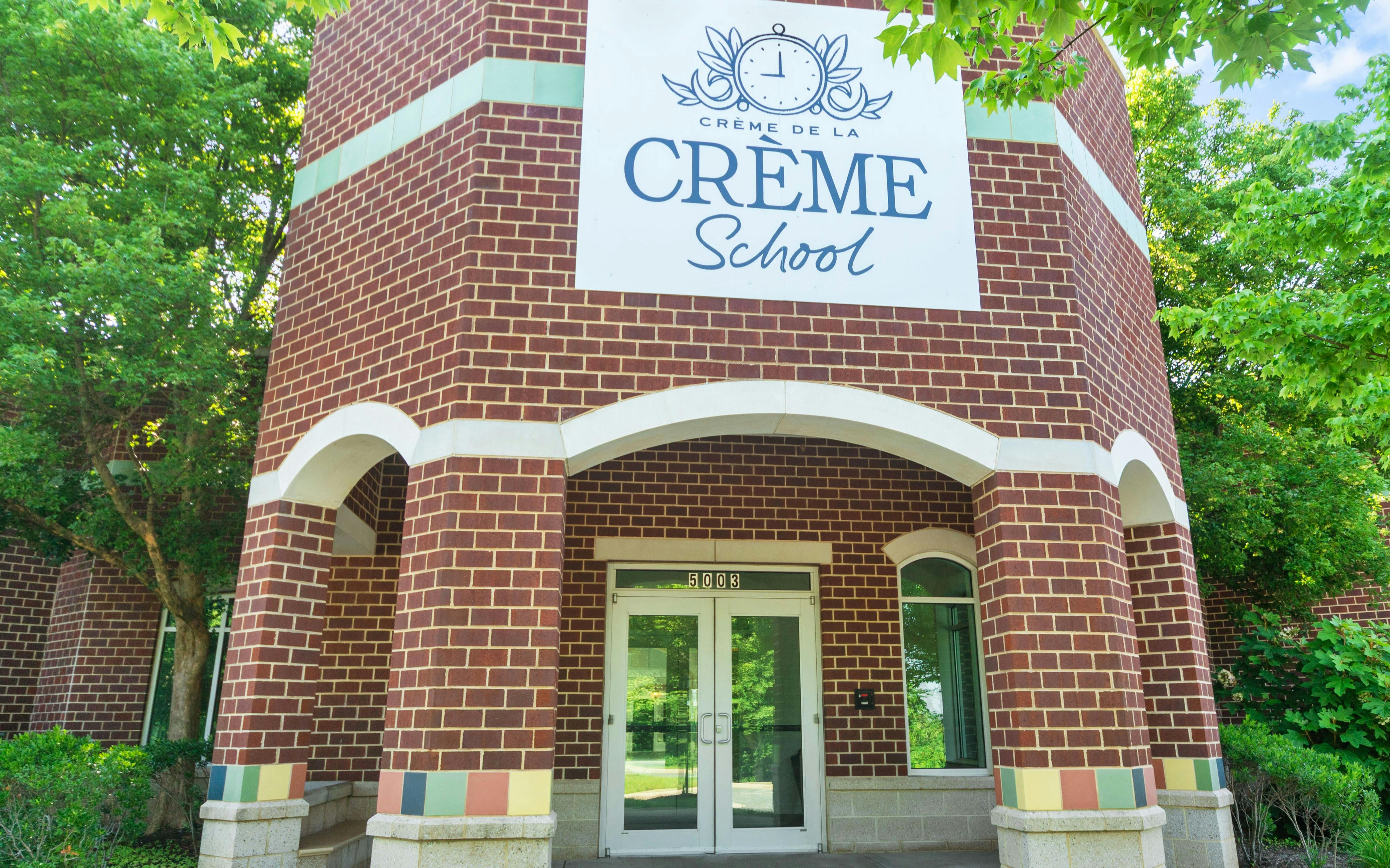 Creme de la Creme School sign on a brick building entrance