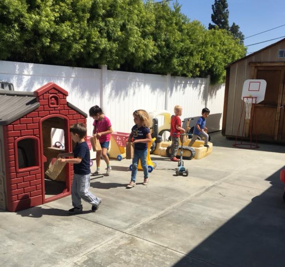 Children playing outdoors with a playhouse and toys
