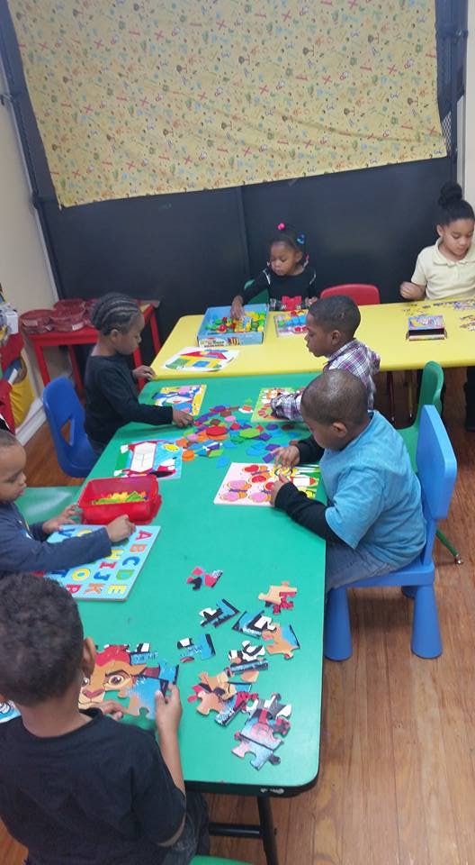 Children sitting at tables playing with puzzles and learning materials in a classroom