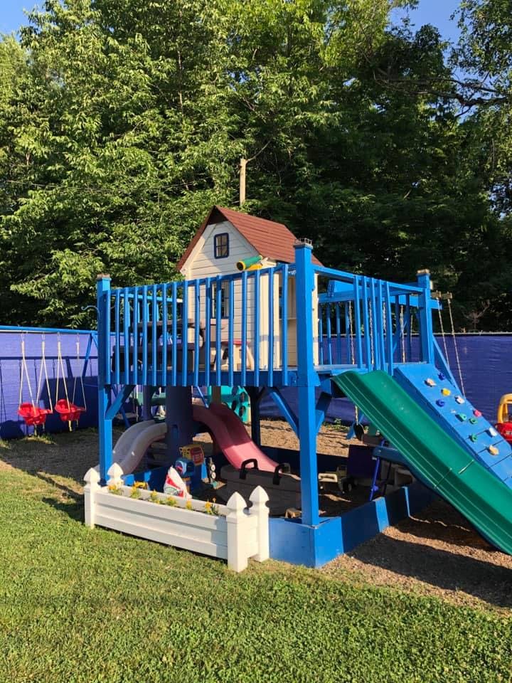 Outdoor playground with blue structure, slides, swings, and a small playhouse