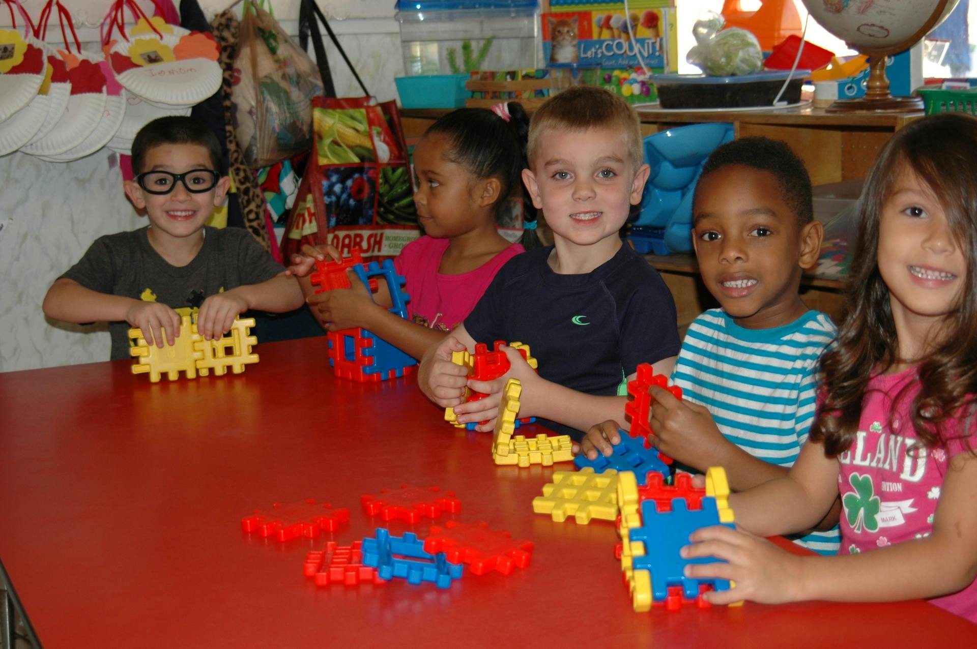 Four children playing with interlocking blocks at a table