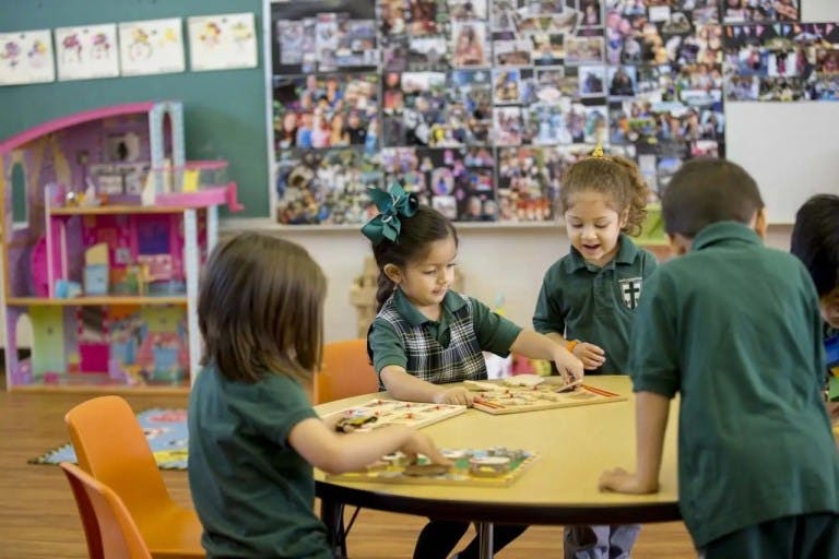 Children playing with puzzles at a table in a classroom