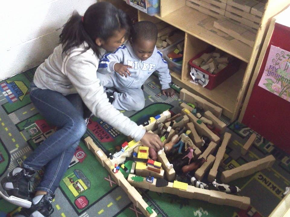 Person and child playing with blocks on a rug