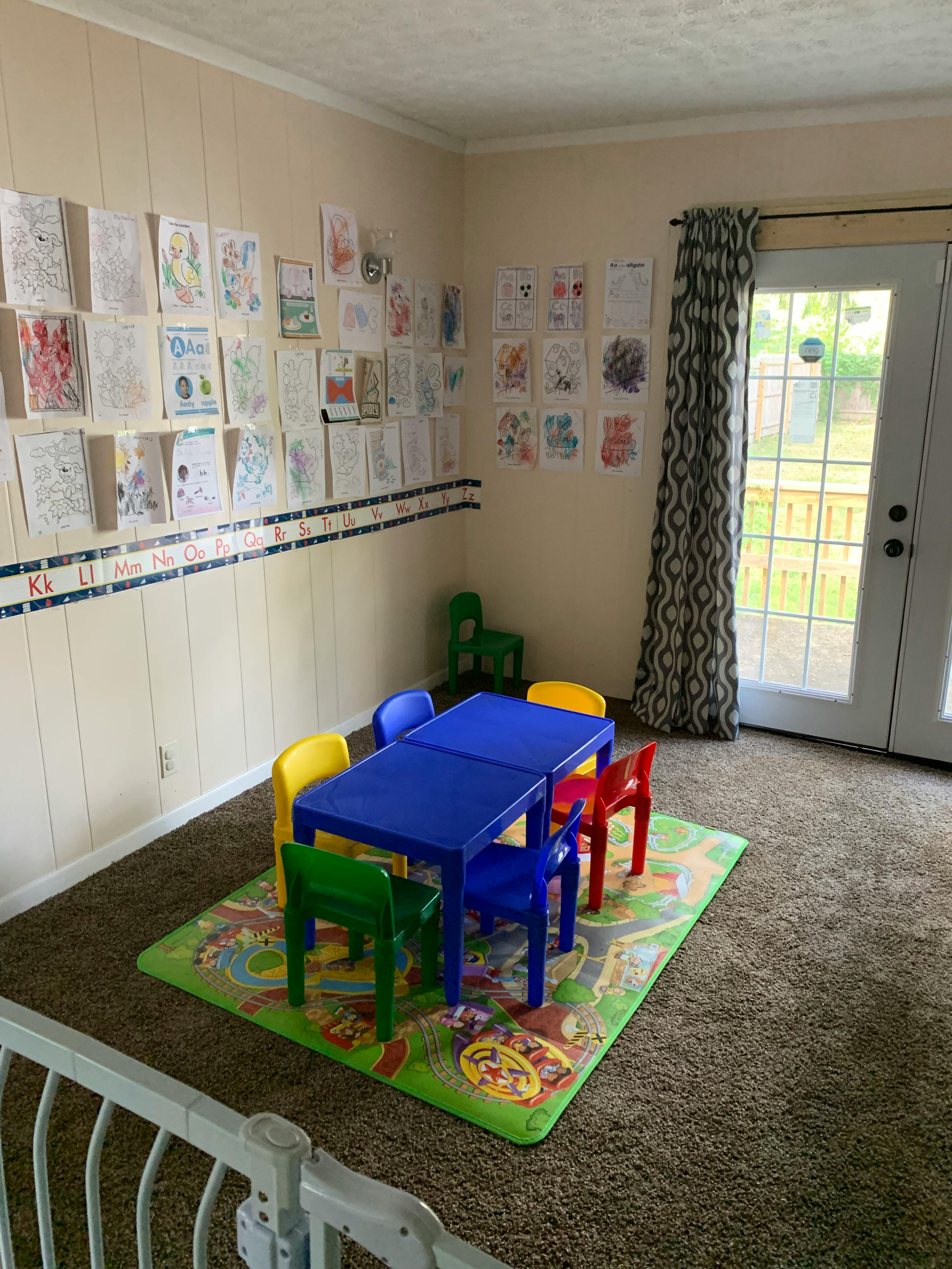 Children's play area with a blue table and colorful chairs on a rug