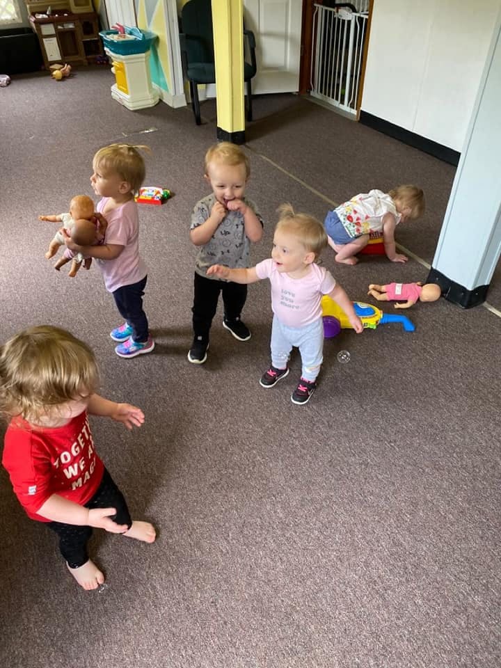 Four children playing with toys on a carpeted floor