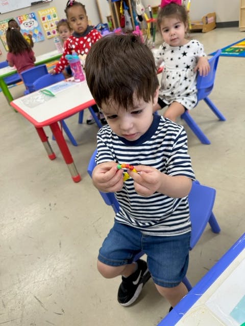 Child in a classroom holding a small toy