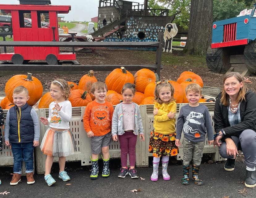 Adult and children posing in front of pumpkins