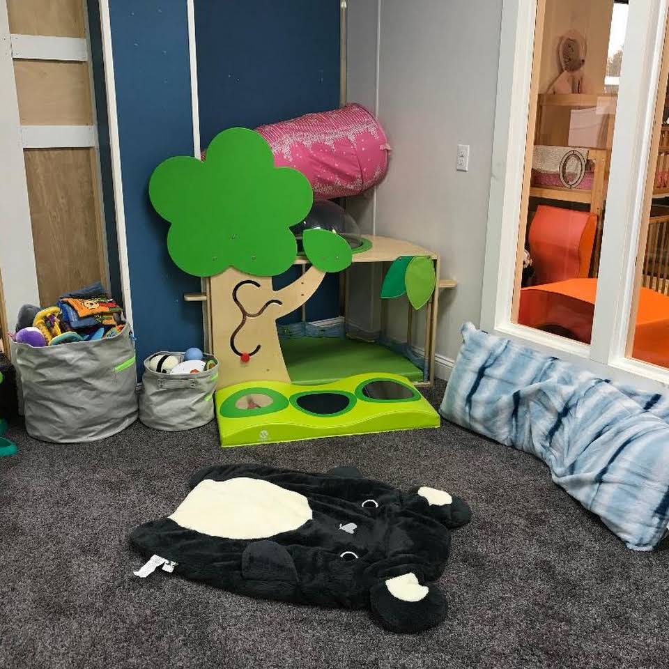 Playroom with a tree-shaped toy, toy bins, and a black animal-shaped mat