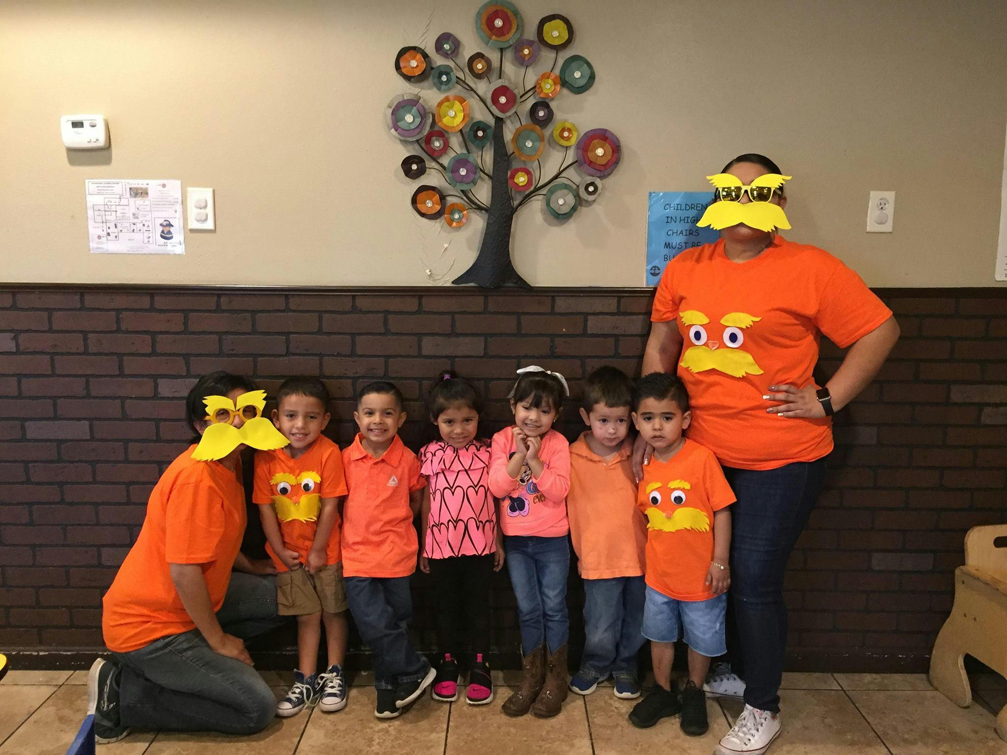 Adults and children wearing orange shirts and yellow masks